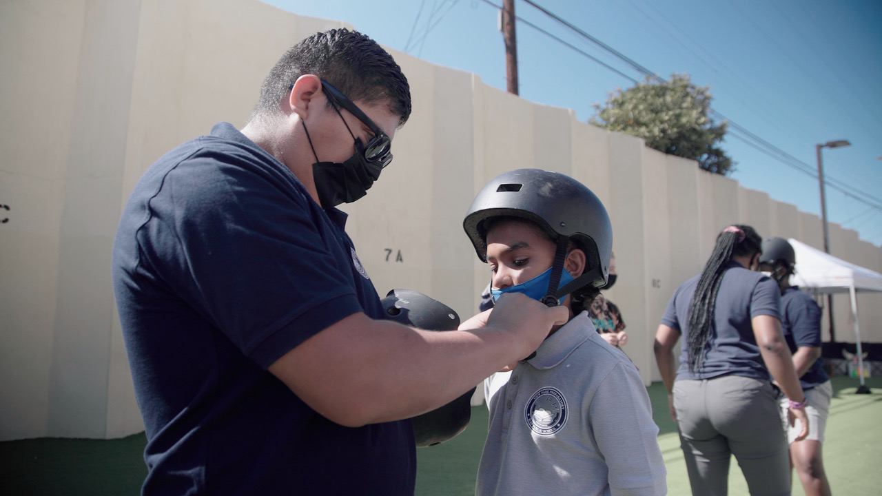 Mr. Mendez helping student secure helmet